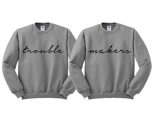 matching sweaters, one says "trouble" the other says "makers"